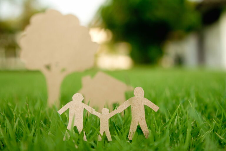 Cardboard family figures cutout sitting on grass
