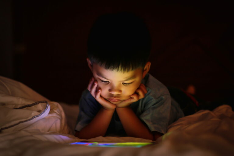 Young boy staring at an iPad at night